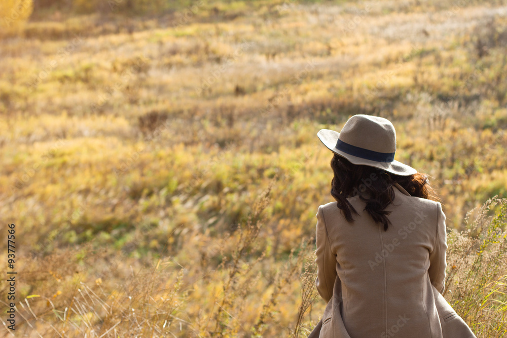 girl in coat and hat sitting and looking into the distance girl in coat and hat sitting and looking into the distance