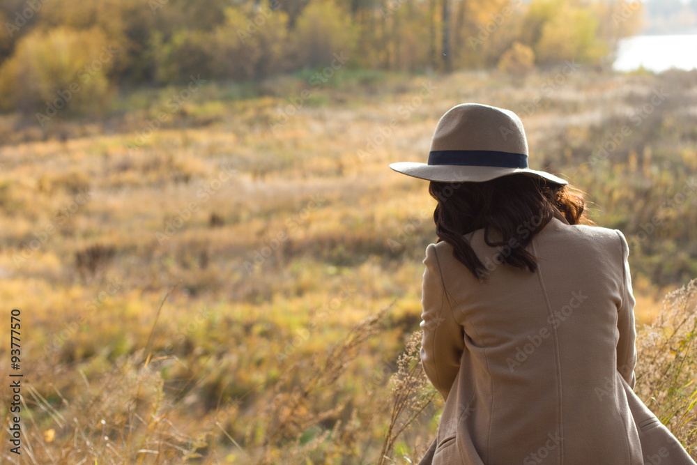 girl in coat and hat sitting and looking into the distance girl in coat and hat sitting and looking into the distance