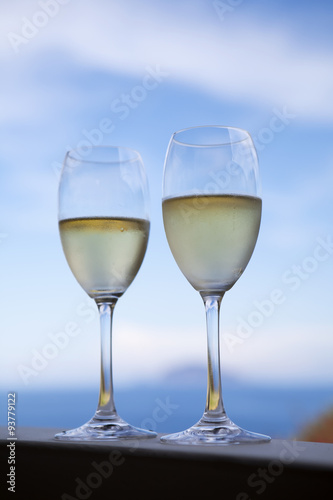 A restaurant table on a beach with glasses of fresh white wine.