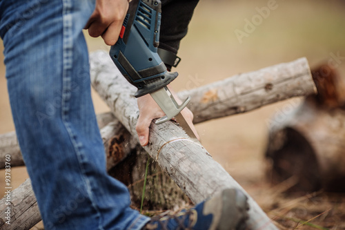 Man cutting a wood with a hand electric saw © kaninstudio