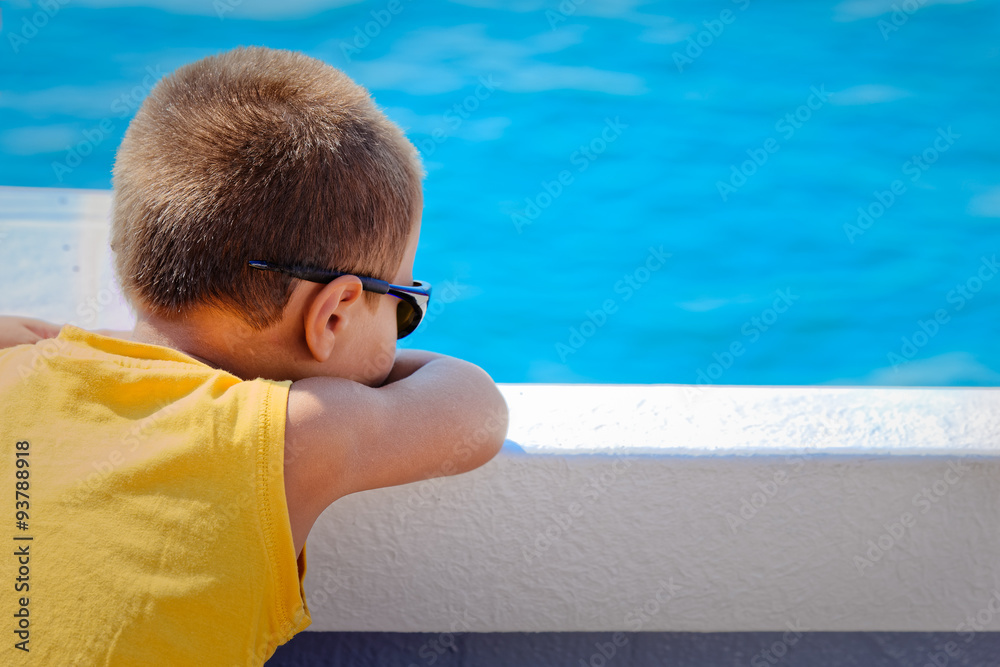 Boy leaning against the wall of a boat looking at the sea
