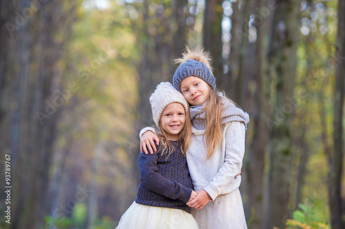 Little adorable sisters at warm sunny autumn day outdoors