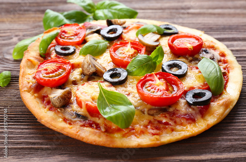 Tasty pizza with vegetables and basil on table close up