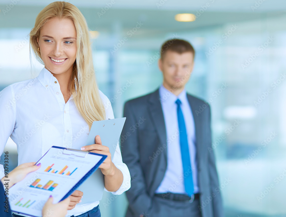 Businesswoman standing in office , holding documents in hand Businesswoman standing in office , holding documents in hand