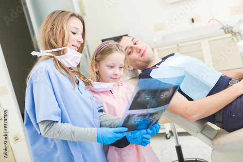 Little dentists looking at x-ray of adult patient