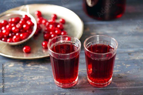 Two glasses with cherry juice on table, on wooden background