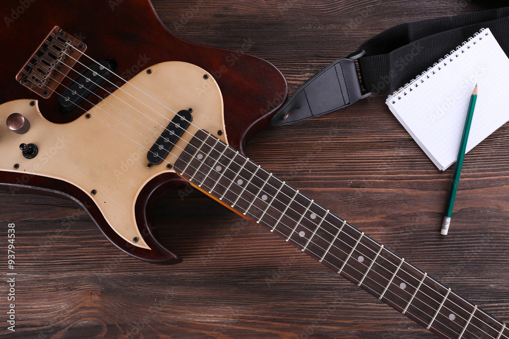 Fototapeta premium Electric guitar with notebook on wooden table close up