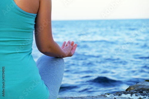 Young woman practicing yoga at seashore