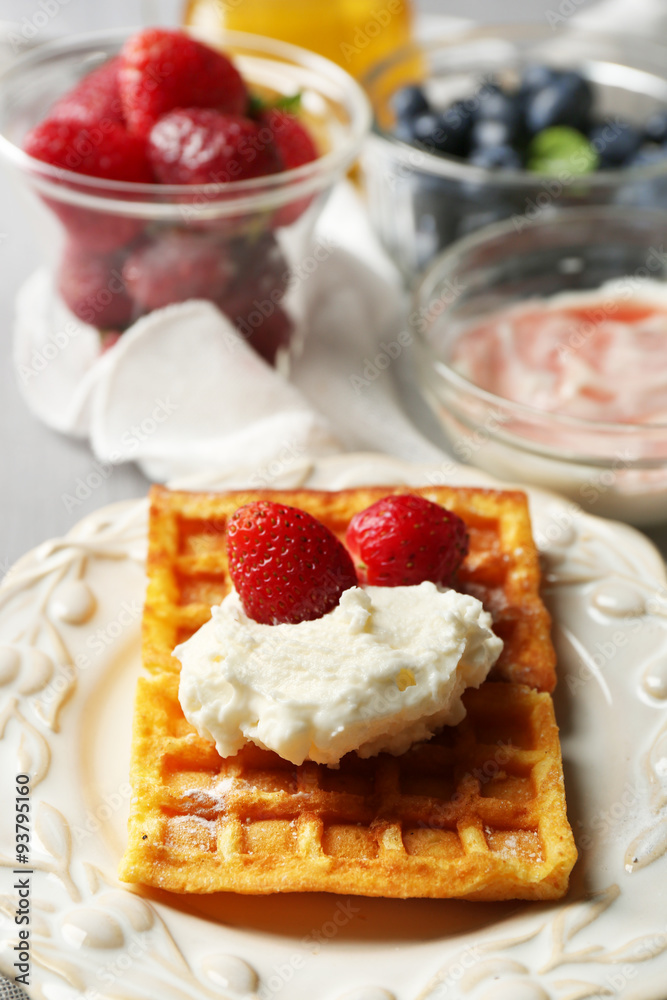 Sweet homemade waffles on plate, on color wooden background Sweet homemade waffles on plate, on color wooden background