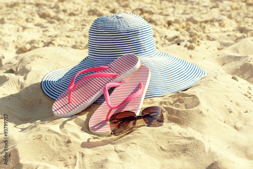 Flip flops, sunglasses and hat on beach sand closeup