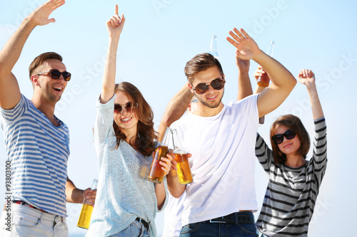 Young people with beer on the riverside