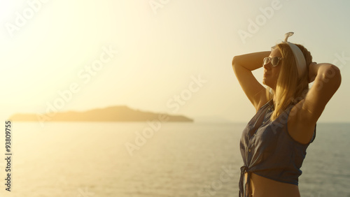 Pretty woman in glasses enjoying sun at sunset.