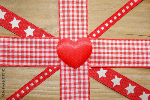 Red ribbon in a union jack design with a red love heart on a rustic wooden surface