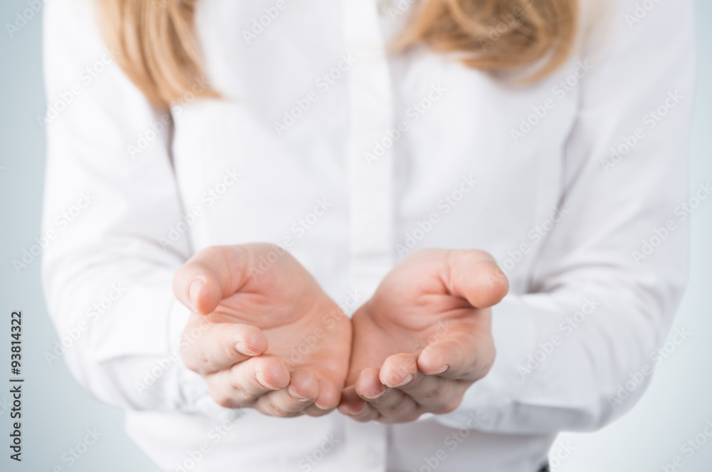 Close-up of blonde's hands, palms up. A woman dressed in formal clothes. A light blue background. Close-up of blonde's hands, palms up. A woman dressed in formal clothes. A light blue background.