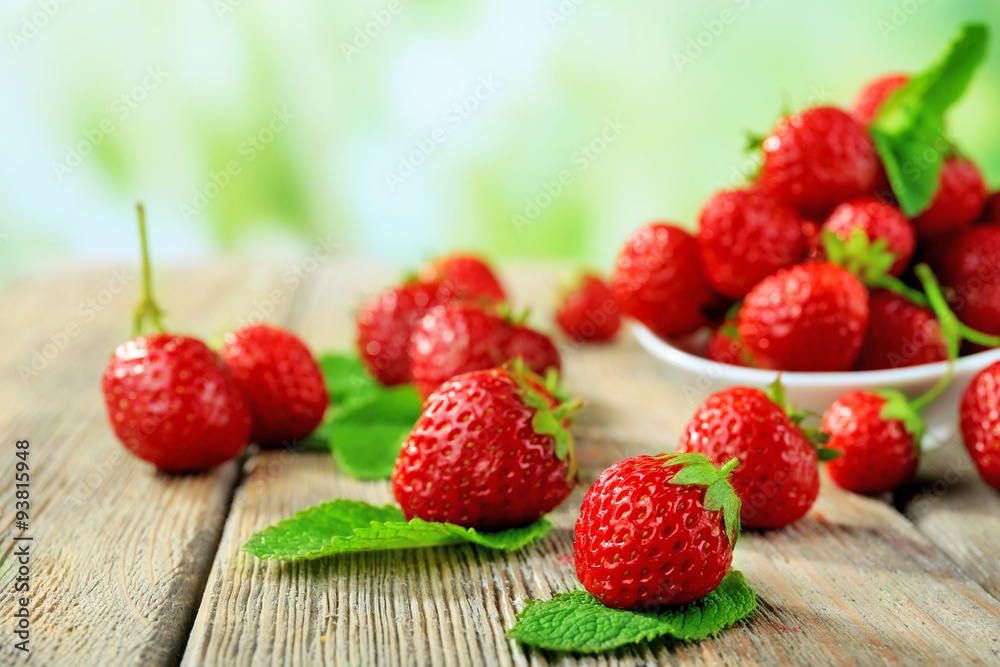 Ripe strawberries in saucer on wooden table on blurred background