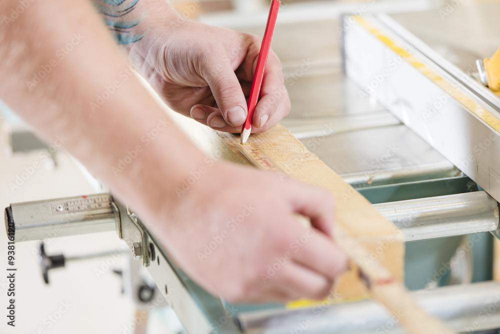 Carpenter measures the length of a wood plank before sawing Carpenter measures the length of a wood plank before sawing