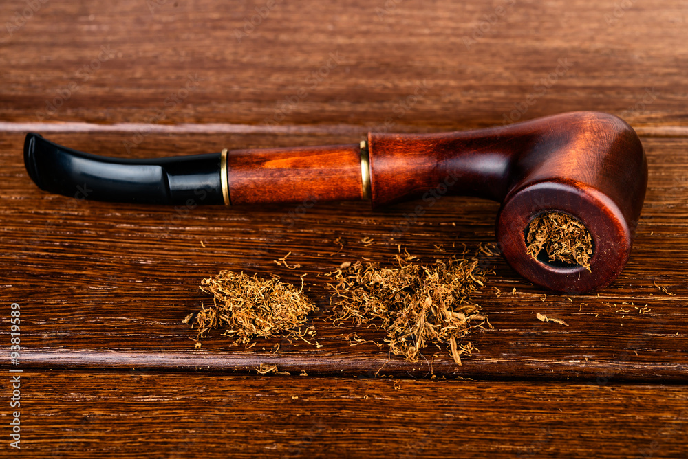 Smoking pipe and tobacco design on wooden background