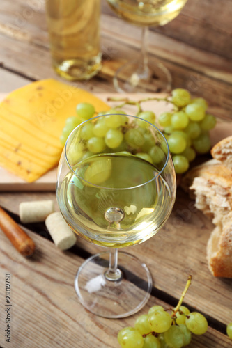 Still life of wine, grape, cheese and bread on rustic wooden background