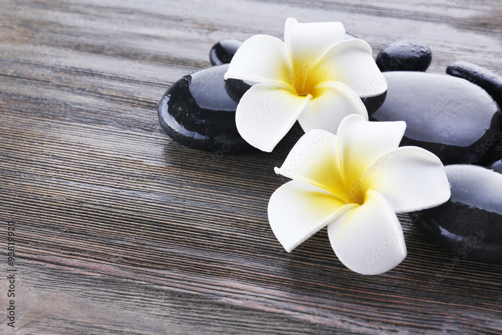 Wet spa stones with flowers on wooden background Wet spa stones with flowers on wooden background
