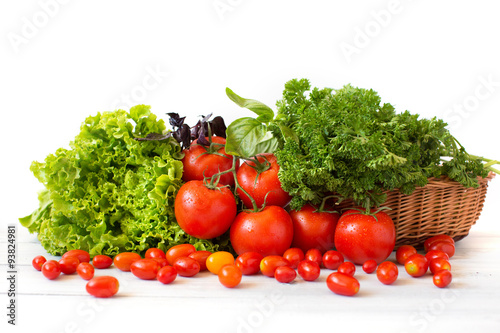 Tomatoes and different herbs in a wicker basket.