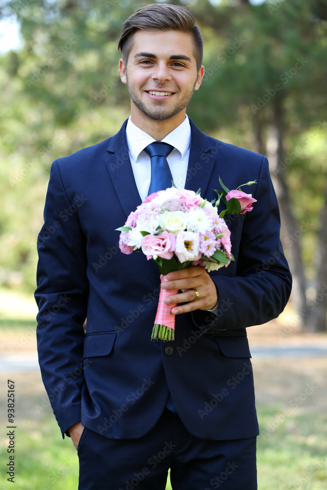 Groom holding wedding bouquet outdoors Groom holding wedding bouquet outdoors