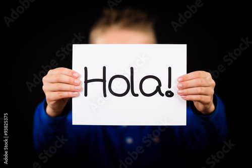 Child holding sign with Spanish word Hola - Hello