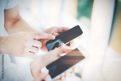 Man and young woman holding in hands their gadgets. The man