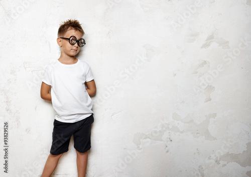 Little boy holds his hands behind back and looks funny