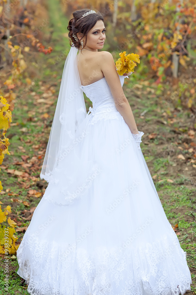 Beautiful bride in autumn forest with bouquet 