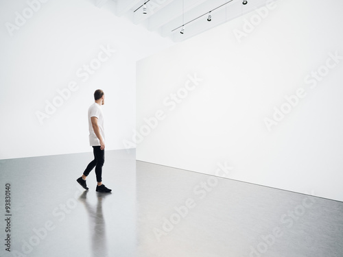Young man walking in the empty, white gallery