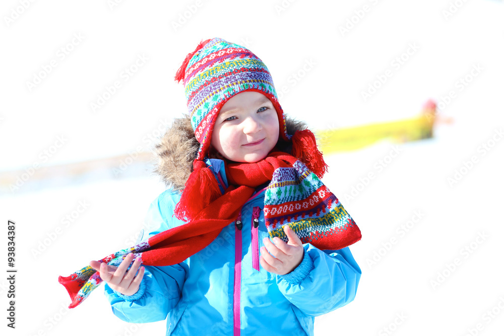 Happy child enjoying winter vacation in Alpine resort in Austria. Little girl playing in the snow. Active sportive toddler learning to ski. Beautiful Alps mountains in the background.