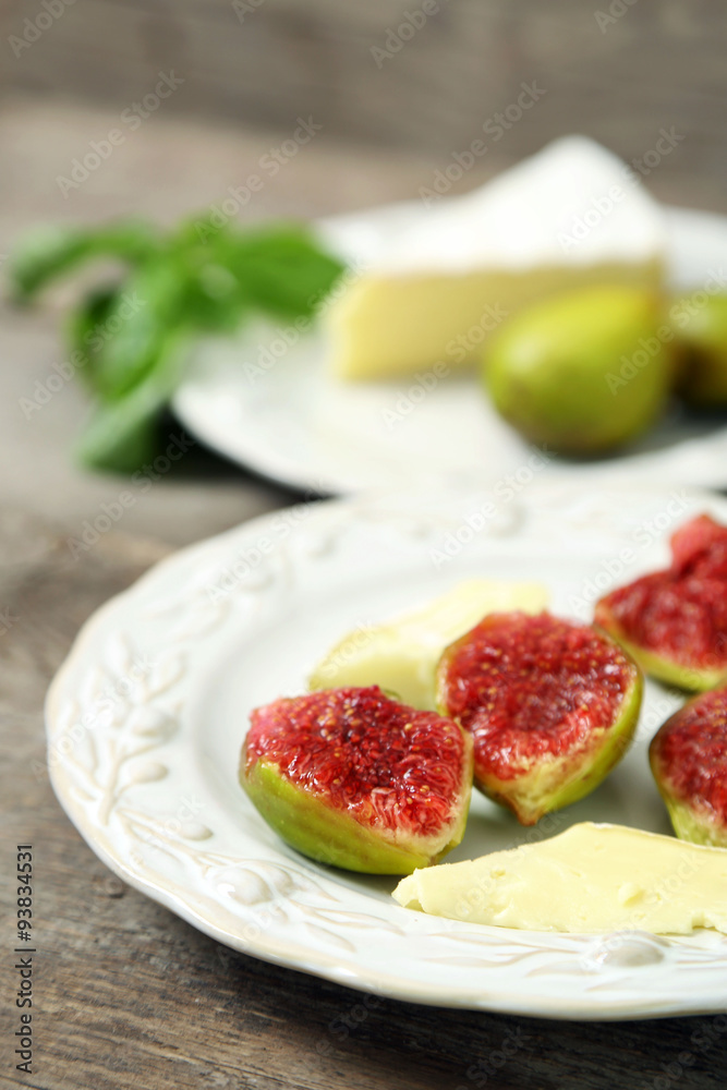 Ripe figs and cheese on plate, on wooden background