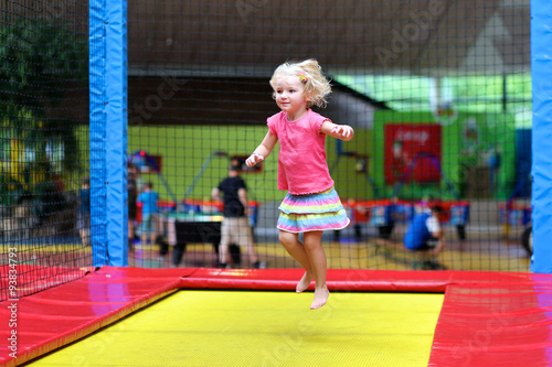 Little child jumping at trampoline in indoors playground. Active toddler girl having fun at sport centre. © cromary