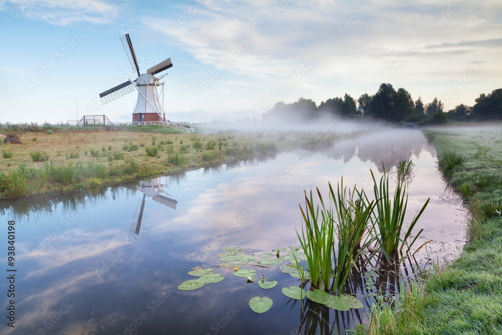 white Dutch windmill in misty morning
