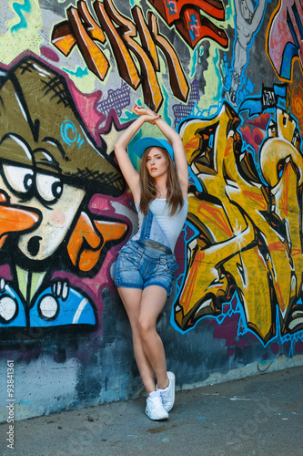 Young girl posing against wall with graffiti