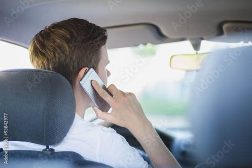 Junger Mann sitzt im Auto und telefoniert