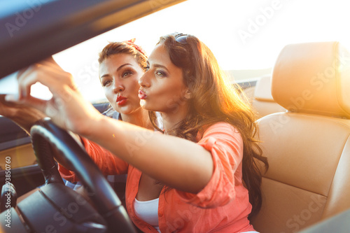 Two young beautiful girls are doing selfie in a convertible © vladstar