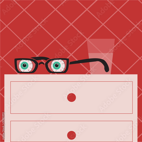 glasses with eyes lying on the bedside table