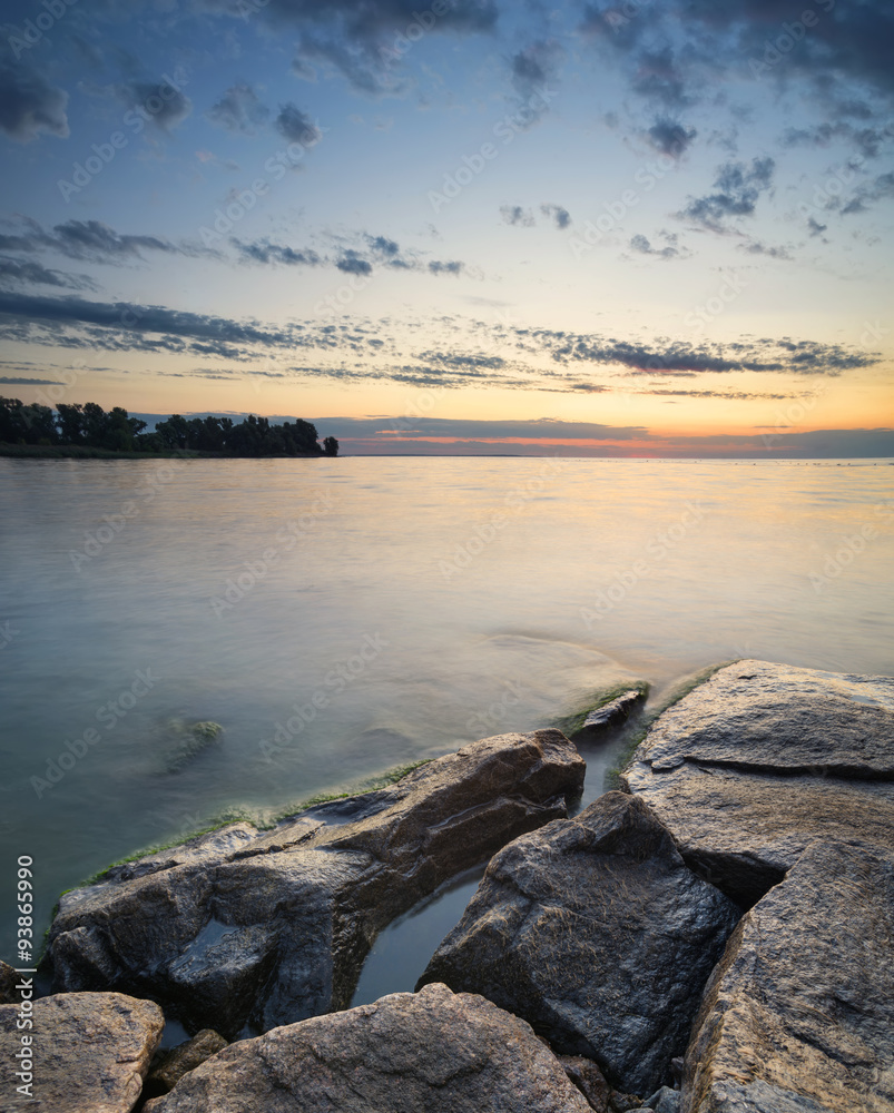 Stones on the sea shore during sunrise. Beautiful natural seascape in the summer time