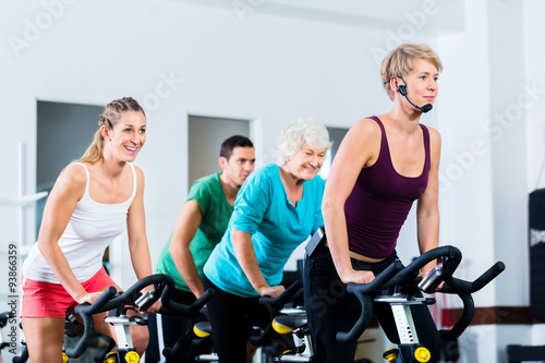 Senior people in gym spinning on fitness bike © Kzenon