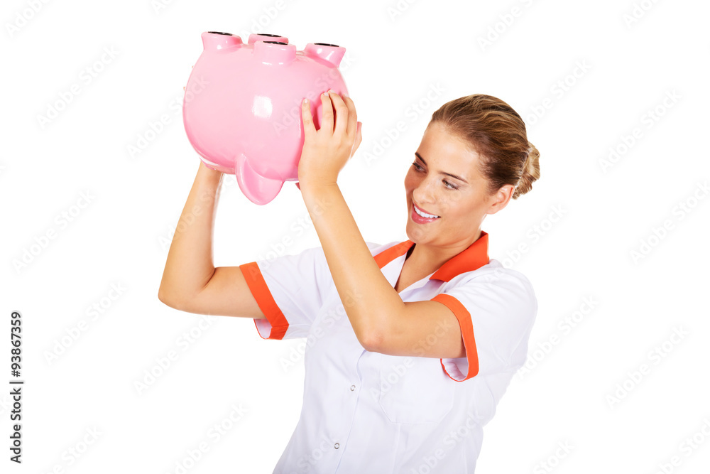 Young beautiful female doctor or nurse holding a piggybank Young beautiful female doctor or nurse holding a piggybank