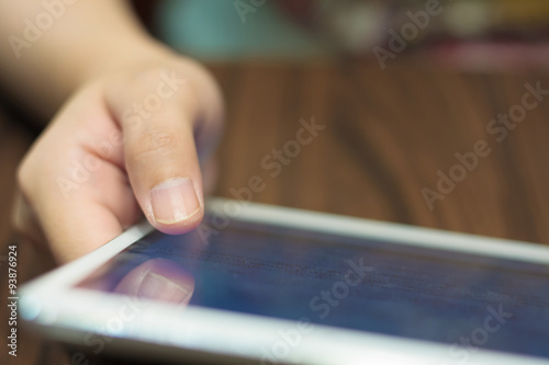 closeup woman hands using tablet computer on wooden table