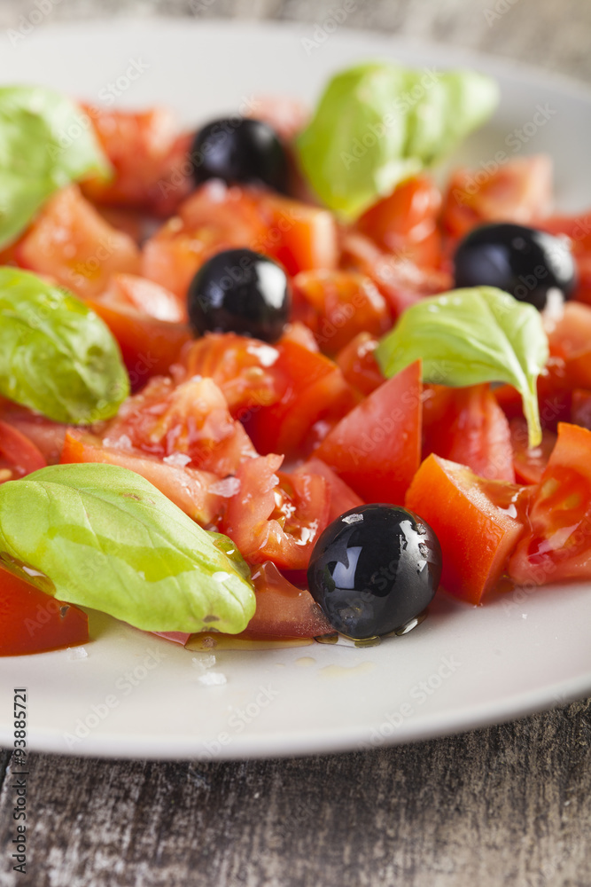 Salad dish with tomato, olives and basil Salad dish with tomato, olives and basil