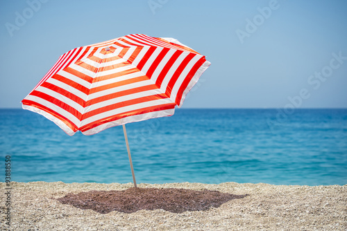 Striped beach umbrella on the beach.

 photo