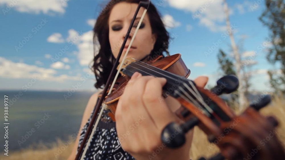 Young woman on the mountain playing the violin on sea background. Steadicam Shot Young woman on the mountain playing the violin on sea background. Steadicam Shot