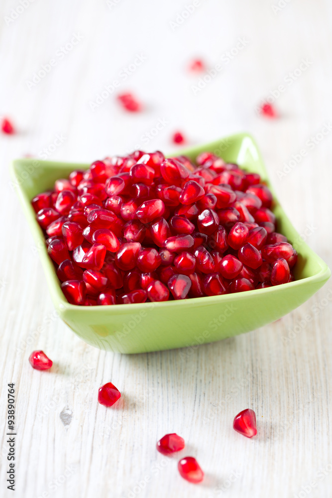 pomegranate seeds in a bowl on wooden surface