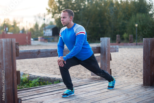 sport man stretching aoutdoors doing exercises evening at sunset. Fitness concepts photo