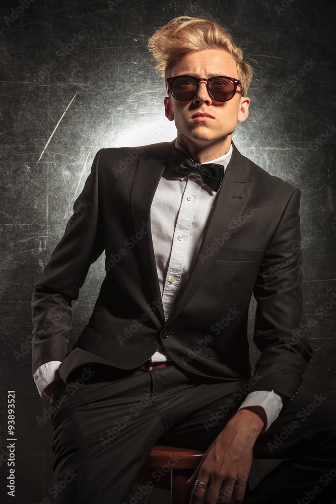 Obraz premium man in tuxedo sitting in studio with hand in pocket