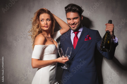 couple holding a bottle of champagne saying cheers photo