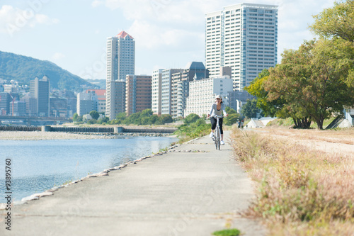 河川敷を自転車で走る日本人女性